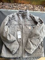 Front view of grey Carhartt work jacket with tags, showing pockets and logos