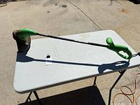 Full view of green corded electric string trimmer on table