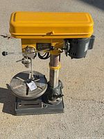 Front angle of AMT yellow drill press showing base, column, table, head