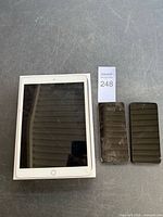 Front view of iPad on box beside two smartphones