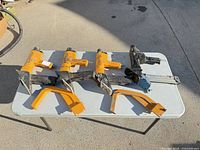 Four Bostitch nailers and two yellow foot plates on table