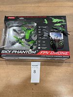 Front of boxed Syma Sky Phantom FPV Drone showing drone through window and accessories