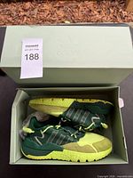 Sneakers inside original light green Adidas box with lot tag visible