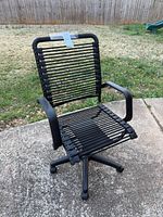 Front angled view of black bungee cord office chair outside on pavement