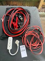 Lot overview showing jumper cables, extension cord, power strip