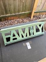 Front view of wooden wall shelf showing FAMILY lettering and decorative trim
