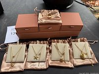 Full set: four necklaces on display pads, ring on pouch, branded boxes