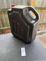 Front view of black plastic oil drain container showing molded handle and body