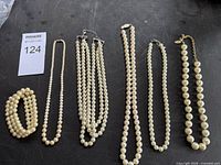 All six faux pearl pieces laid out on dark surface