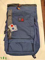 Front view showing roll-top closure, logo patch, front pocket and overall color