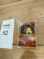 Front view of Charizard Base Set holo card in protective case beside lot number card