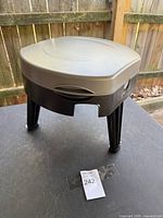 toilet folded with legs extended, lid closed, front carry cutout visible