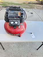 Full view of Porter-Cable pancake air compressor on table showing red tank, black motor housing, top label