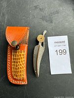 Knife folded beside leather sheath showing overall lot