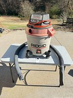 Ridgid 12-gallon shop vacuum with hose, adapters and cord on outdoor table