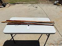 Three wooden walking sticks laid on folding table outdoors
