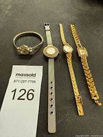 Four wristwatches laid out beside lot number