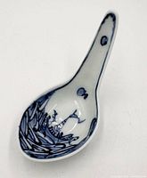Top view of blue and white porcelain soup spoon showing painted landscape decoration