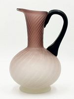 Full view of pitcher showing pink to white gradient, swirl pattern, black handle