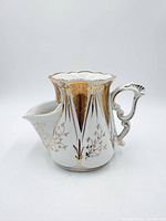 Front view of porcelain scuttle shaving mug showing handle, spout, gold decoration