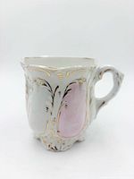 Side view showing embossed pink panel, gold gilt, handle and footed base