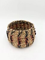 Side view of coiled pine needle basket showing raffia stitches and bead accents