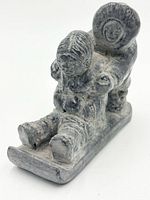 Front angled view of soapstone carving showing child seated on sled and adult figure pushing