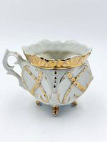 Side view showing raised gilt design, handle and feet