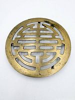 Front view of brass Shou longevity trivet