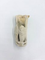 Front view showing carved face, beard and hollow opening