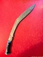 Full view of recurved kukri knife on red surface