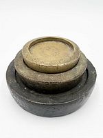 Oblique view of three stacked brass cup weights showing patina and nesting form