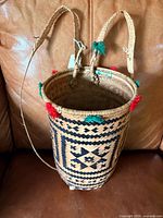 Full view of woven basket showing straps, feet, tassels