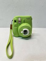 Front view of green Fujifilm Instax Mini 9 with wrist strap