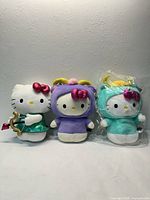 Three Hello Kitty plush dolls upright