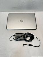 Closed silver HP Envy Beats laptop with charger