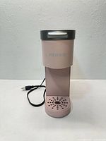 Front view of pink Keurig coffee maker with power cord visible