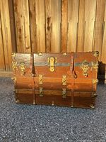 Front view showing wood panels, brass hardware and leather straps