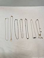 All seven necklaces laid flat in a row for full overview