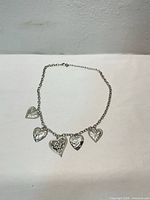 Full view of silver-tone charm necklace with five heart charms