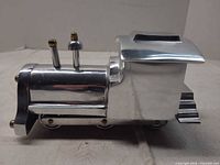 side view of polished aluminum locomotive showing brass knobs and rolling wheels