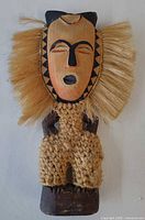 Front view showing mask face, raffia mane, braided raffia body wrap