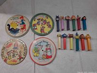 Group shot of 4 picture records and 12 candy dispensers on white surface