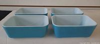 Four blue exterior white interior Pyrex loaf pans front view
