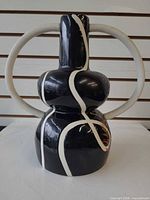 front view of black ceramic vase with white lines and handle