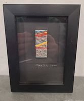 Front view of framed miniature artwork showing matchbox painting centered and signature below