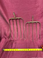 Both pitchfork heads side-by-side with measuring tape for scale