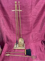 Full view of brass fireplace tool set on stand with additional Alfred finial poker and brush laid in front