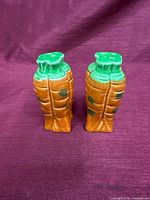 Front view of both carrot-shaped shakers showing color and form