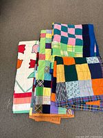 Stack of four handmade quilts on floor displaying varied patchwork patterns and tulip print